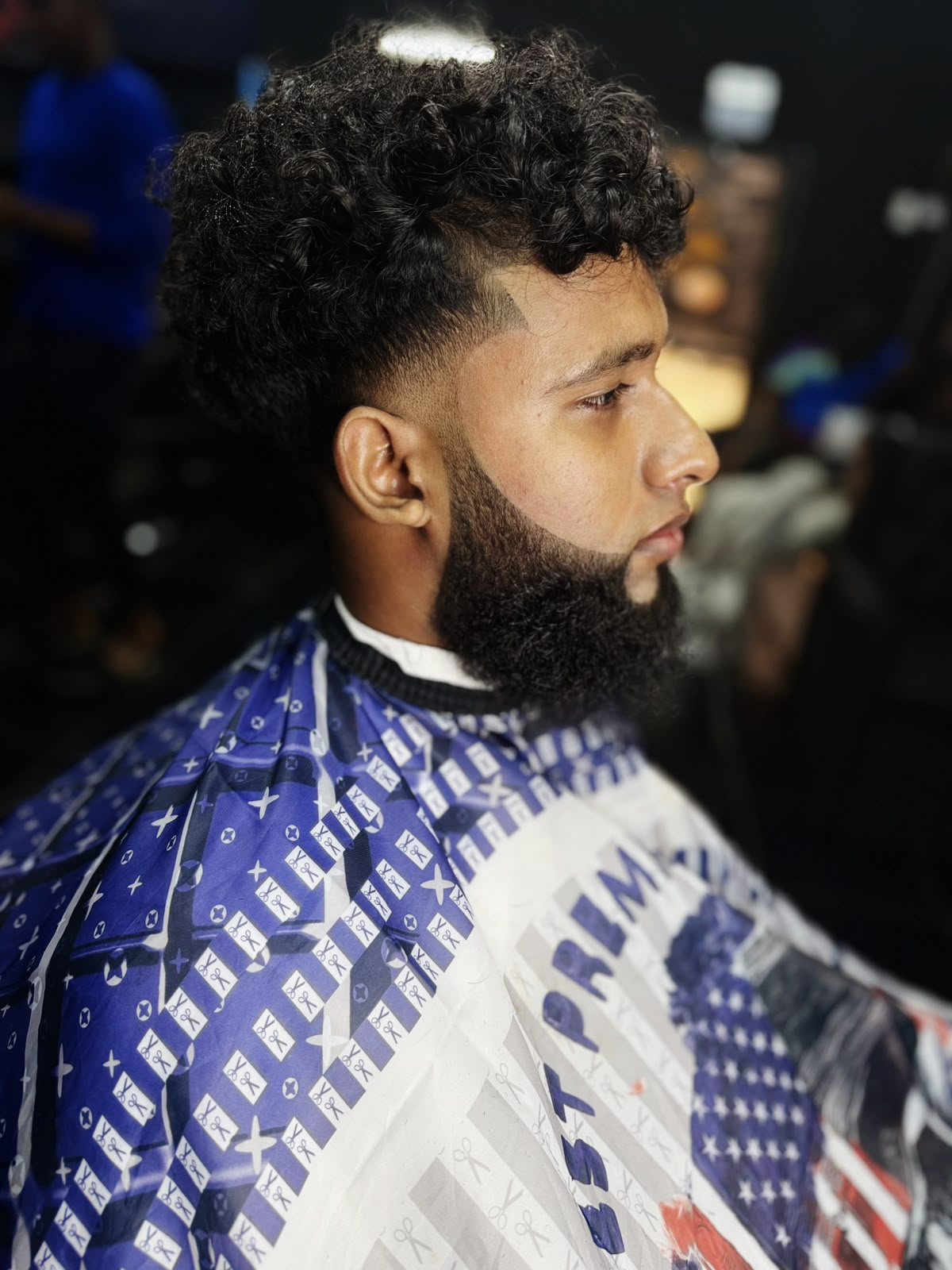 Curly textured haircut with clean fade and sculpted beard